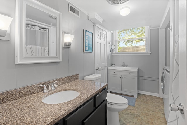 bathroom with washing machine and clothes dryer, vanity, and toilet