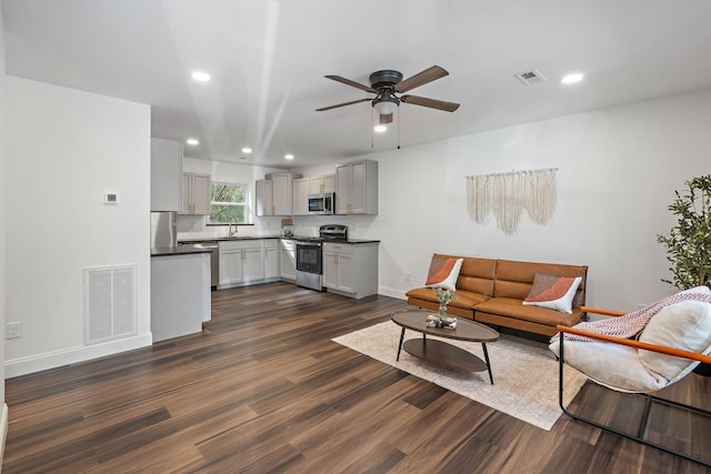 living room featuring ceiling fan, sink, and dark hardwood / wood-style floors