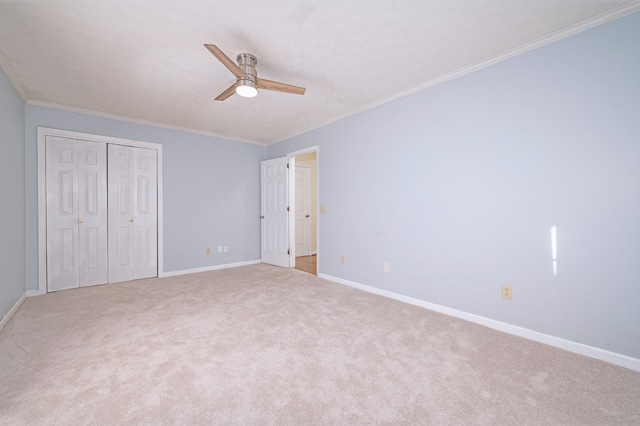 unfurnished bedroom with ornamental molding, a closet, light colored carpet, and ceiling fan