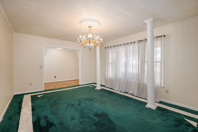 carpeted empty room featuring ornamental molding, a textured ceiling, a chandelier, and decorative columns