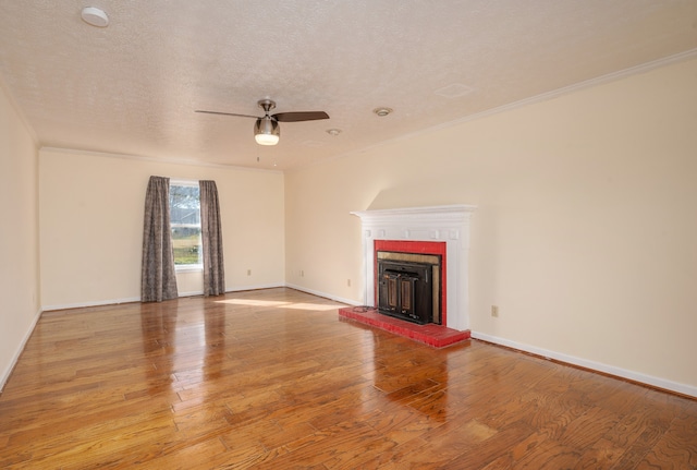 unfurnished living room featuring a brick fireplace, light hardwood / wood-style floors, a textured ceiling, ceiling fan, and crown molding