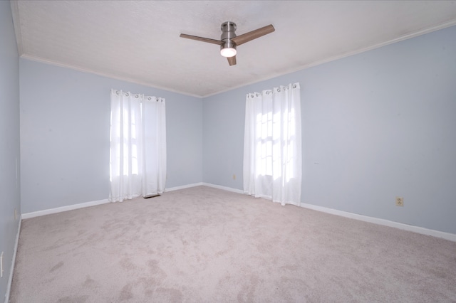 unfurnished room with ceiling fan, light colored carpet, and crown molding