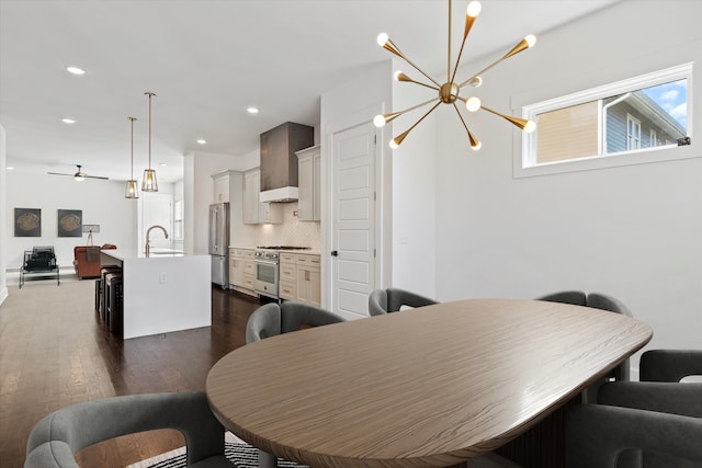 dining area featuring dark hardwood / wood-style flooring, ceiling fan with notable chandelier, and sink