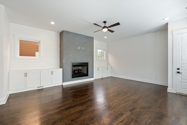 unfurnished living room with a fireplace, ceiling fan, and dark wood-type flooring