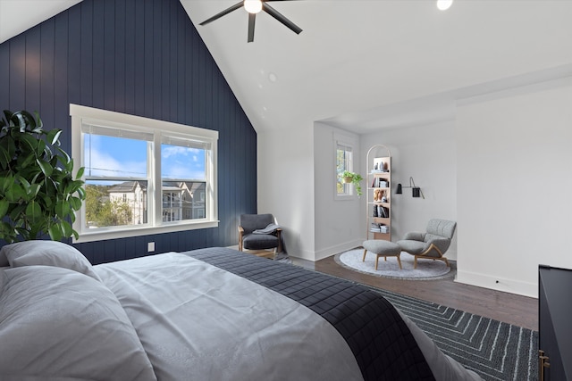 bedroom with hardwood / wood-style flooring, ceiling fan, wood walls, and vaulted ceiling