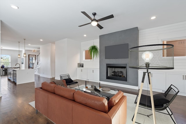 living room with ceiling fan, a fireplace, dark hardwood / wood-style floors, and wooden walls