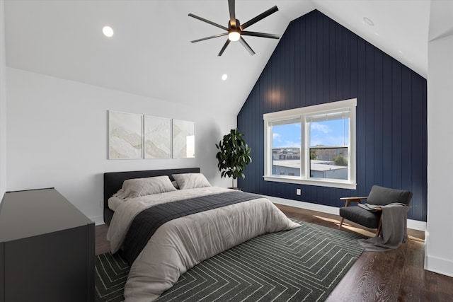 bedroom with wood-type flooring, vaulted ceiling, ceiling fan, and wooden walls