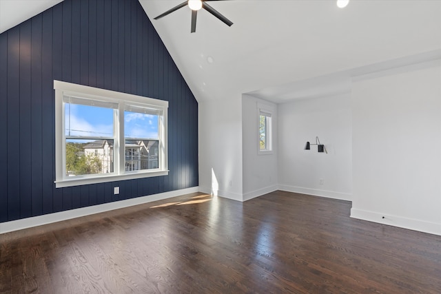 additional living space featuring wood walls, ceiling fan, dark wood-type flooring, and vaulted ceiling