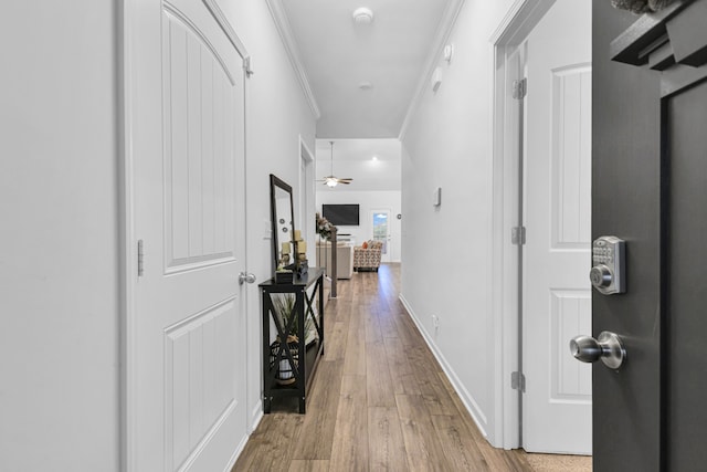 hall with light wood-type flooring and crown molding