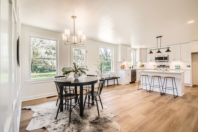 dining space featuring light wood-type flooring, plenty of natural light, and a chandelier