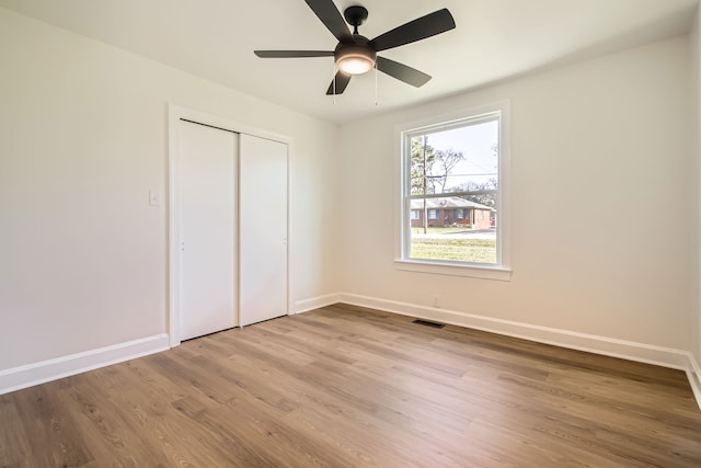 unfurnished bedroom featuring wood-type flooring, ceiling fan, and a closet