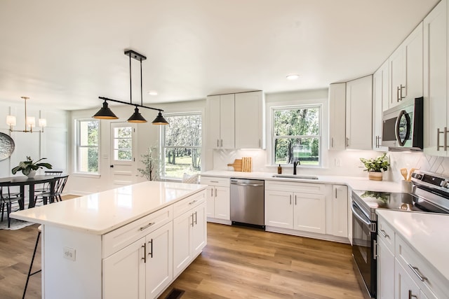 kitchen with white cabinets, pendant lighting, a wealth of natural light, and stainless steel appliances