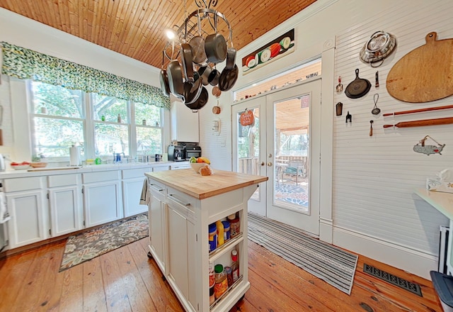 kitchen featuring a wealth of natural light, white cabinetry, french doors, and decorative light fixtures