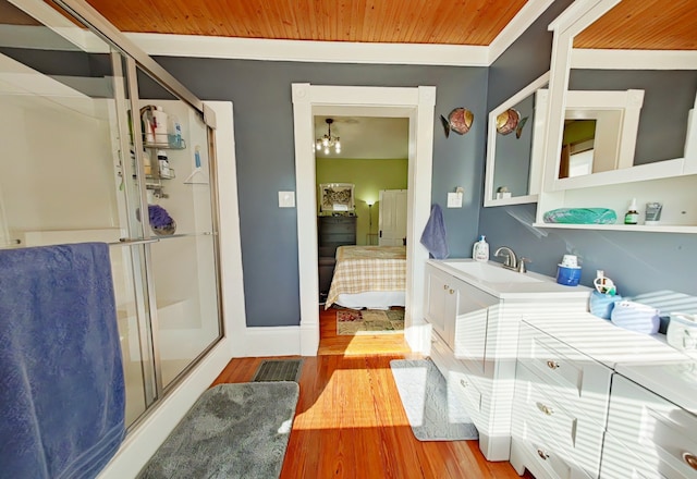 bathroom featuring hardwood / wood-style flooring, vanity, walk in shower, and an inviting chandelier