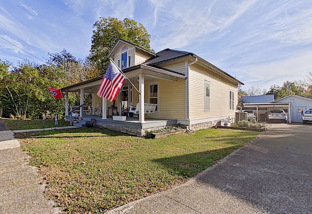 view of front facade featuring a front yard, a porch, an outbuilding, and a garage