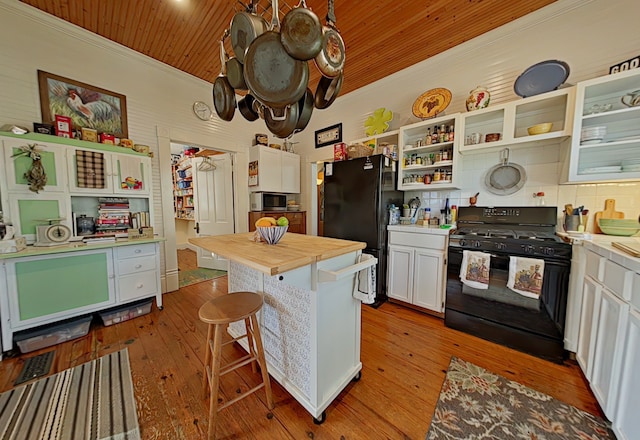 kitchen featuring light wood-type flooring, black appliances, a center island, white cabinetry, and a breakfast bar area