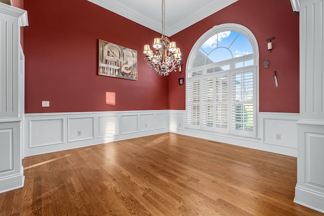 spare room featuring crown molding, plenty of natural light, hardwood / wood-style floors, and a notable chandelier