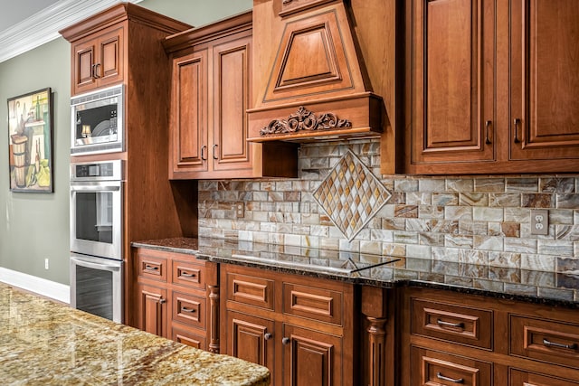 kitchen with premium range hood, appliances with stainless steel finishes, backsplash, ornamental molding, and dark stone counters