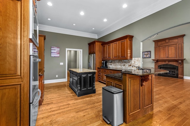 kitchen with a kitchen breakfast bar, a center island, a high end fireplace, stainless steel refrigerator with ice dispenser, and light wood-type flooring