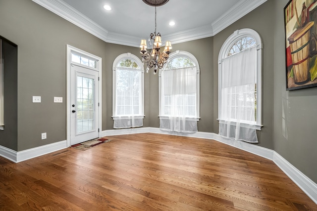 unfurnished dining area with hardwood / wood-style flooring, ornamental molding, and a chandelier