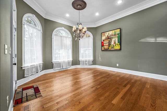 unfurnished dining area featuring crown molding, wood-type flooring, and a notable chandelier