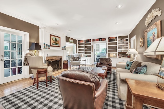 living room featuring built in shelves, light hardwood / wood-style flooring, and ornamental molding