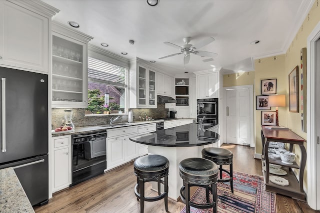 kitchen with black appliances, white cabinetry, backsplash, and a breakfast bar