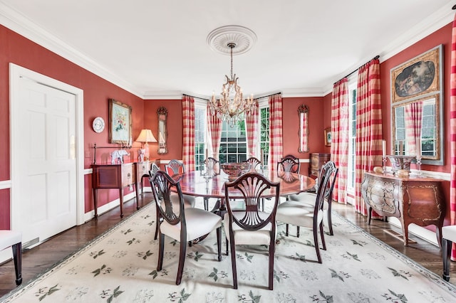 dining area with ornamental molding, hardwood / wood-style flooring, and an inviting chandelier