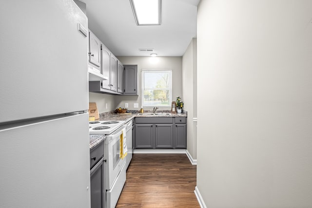 kitchen featuring white appliances, sink, dark hardwood / wood-style flooring, and gray cabinets