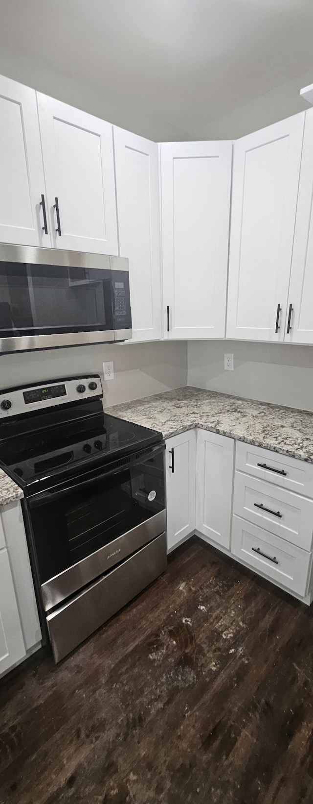 kitchen with dark hardwood / wood-style floors, light stone countertops, white cabinetry, and stainless steel appliances