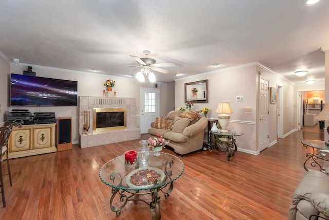 living room with hardwood / wood-style floors, a fireplace, ceiling fan, and crown molding