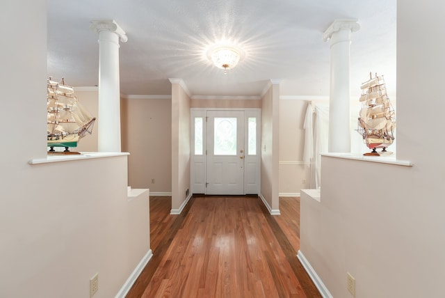 doorway to outside with hardwood / wood-style floors, crown molding, and decorative columns