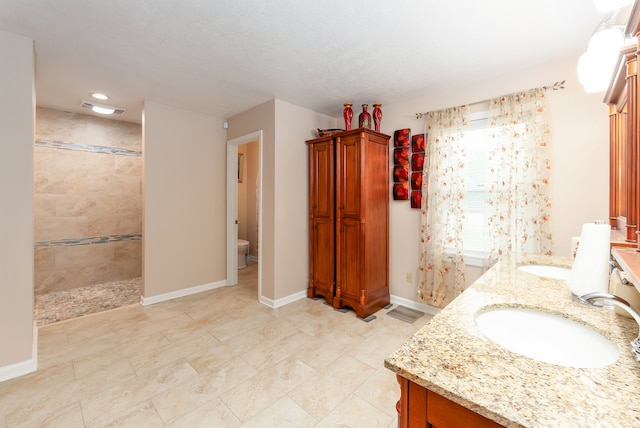 bathroom featuring toilet, vanity, and a tile shower