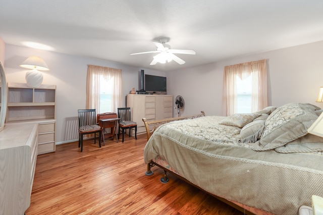 bedroom featuring ceiling fan, multiple windows, and light wood-type flooring