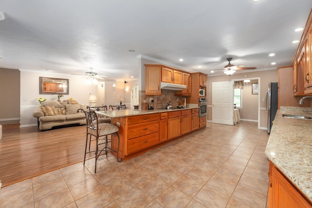 kitchen with tasteful backsplash, light stone counters, ornamental molding, appliances with stainless steel finishes, and sink