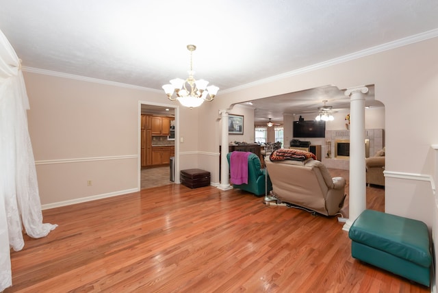 living room with decorative columns, ceiling fan with notable chandelier, light wood-type flooring, and ornamental molding