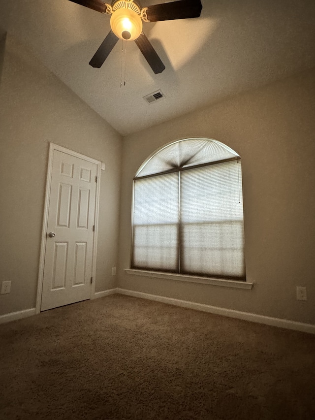 unfurnished bedroom featuring lofted ceiling, carpet flooring, a ceiling fan, visible vents, and baseboards