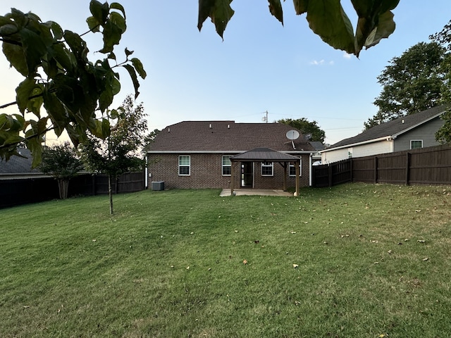 back of house featuring a fenced backyard, a lawn, and a gazebo