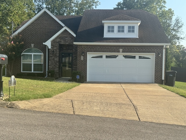 view of front of house featuring driveway, a shingled roof, an attached garage, a front lawn, and brick siding