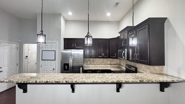 kitchen featuring a peninsula, appliances with stainless steel finishes, a breakfast bar, and pendant lighting