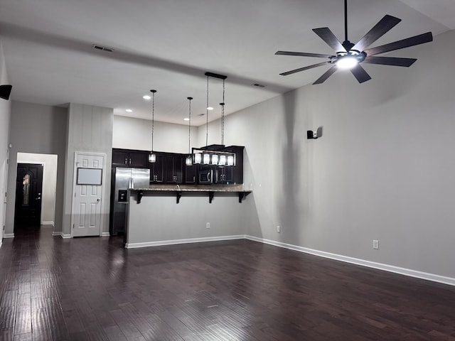 kitchen with visible vents, a breakfast bar area, dark wood-type flooring, a peninsula, and stainless steel appliances