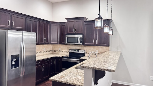 kitchen with tasteful backsplash, appliances with stainless steel finishes, a kitchen bar, and pendant lighting