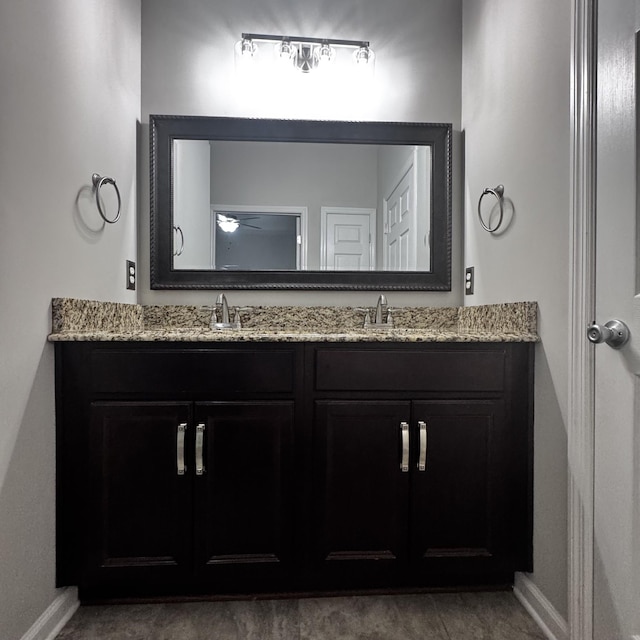 bathroom featuring a sink, baseboards, and double vanity