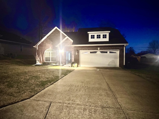 traditional home with a garage, driveway, brick siding, and a lawn