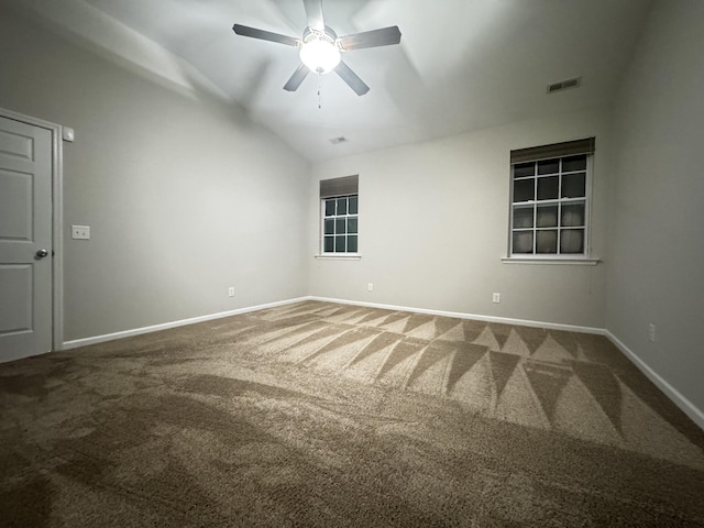 empty room with vaulted ceiling, carpet flooring, visible vents, and baseboards