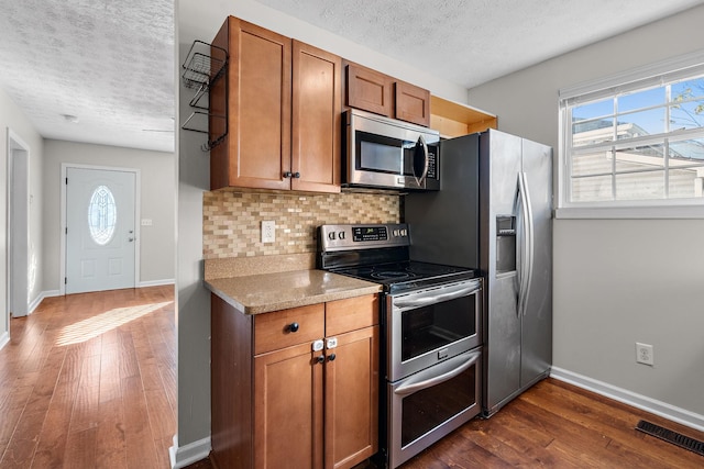 kitchen with tasteful backsplash, light stone counters, a textured ceiling, dark hardwood / wood-style flooring, and stainless steel appliances