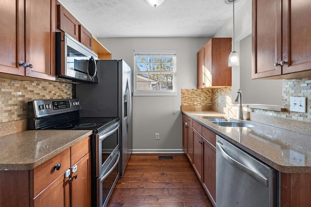 kitchen featuring stainless steel appliances, a textured ceiling, hanging light fixtures, and dark stone countertops