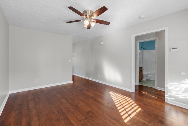 empty room featuring ceiling fan, dark wood-type flooring, and a textured ceiling