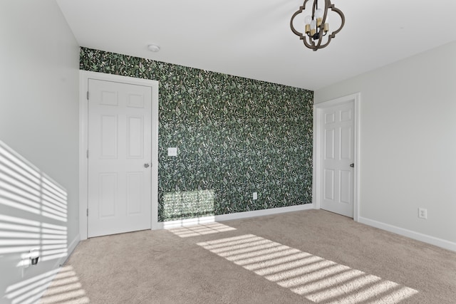 spare room with carpet, a healthy amount of sunlight, and a chandelier