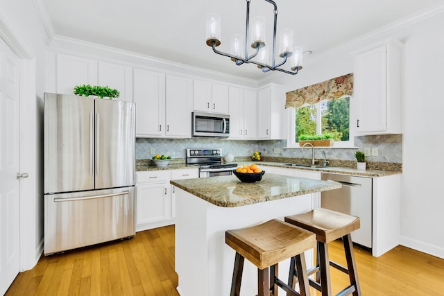 kitchen featuring stainless steel appliances, pendant lighting, light hardwood / wood-style floors, white cabinets, and a center island